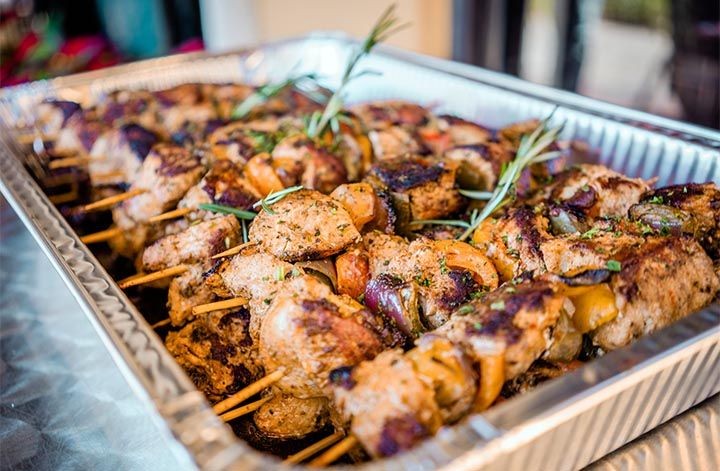 Tray filled with skewers of grilled meat and vegetables, garnished with rosemary sprigs.